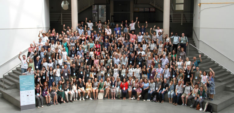 Group photo of MT Summit 2025 participants, featuring researchers and professionals from around the world gathered in a conference hall.
